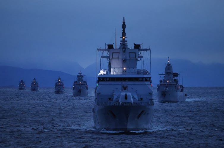 International energy struggles over the sea’s finite assets name for inventive international relations 1 A fleet of military ships at dusk with mountains in the background.