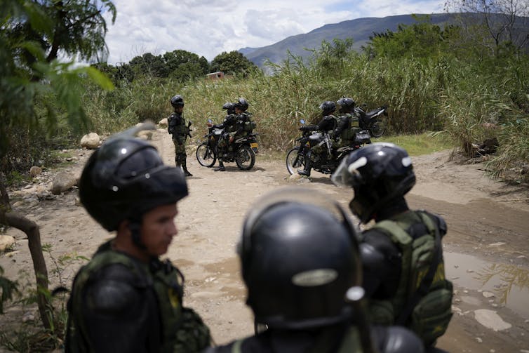 Soldados armados patrullan el camino de tierra.