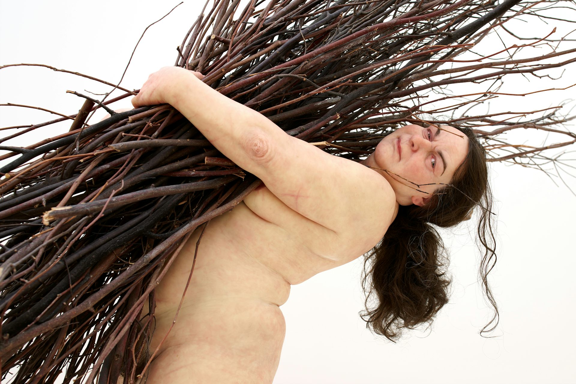 Sculpture: a naked woman holds a bundle of sticks. 
