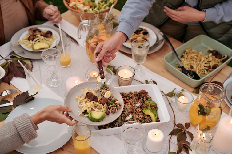 People enjoying a meal together with only their arms visible