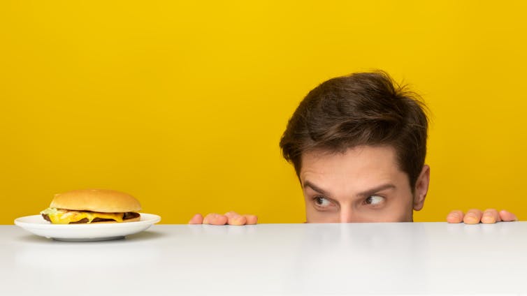 A man eyes a hamburger hungrily.