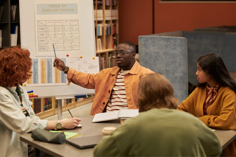 Man teaching English to a group of people in a classroom.