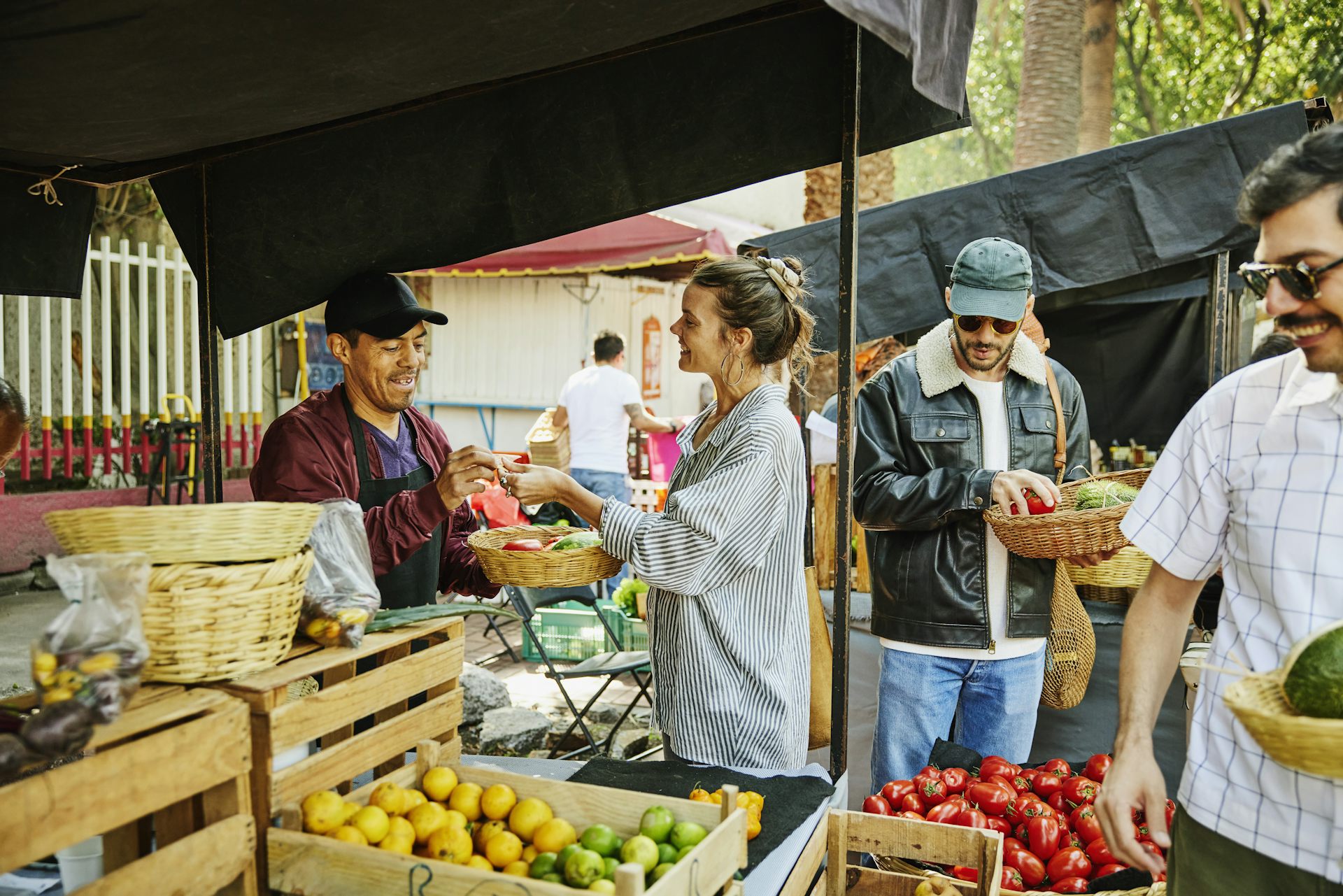 A fruit vendor talks with a customer by his display at a farmers market.