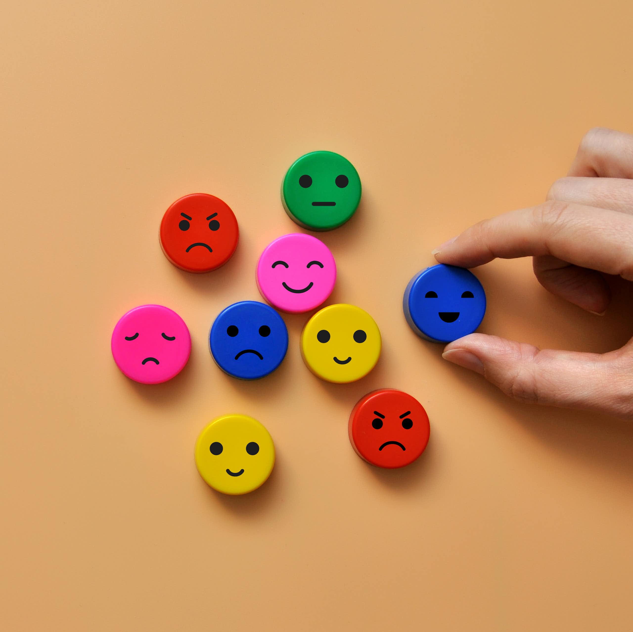 brown background, 9 colourful face discs with different expressions