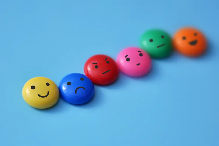 blue background, six round colourful discs with faces expressing different emotions