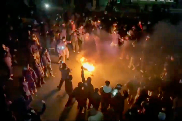 Des manifestants dansent et acclament autour d’un feu de joie