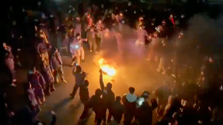 des manifestants autour d’un feu dans une rue de la ville, la nuit