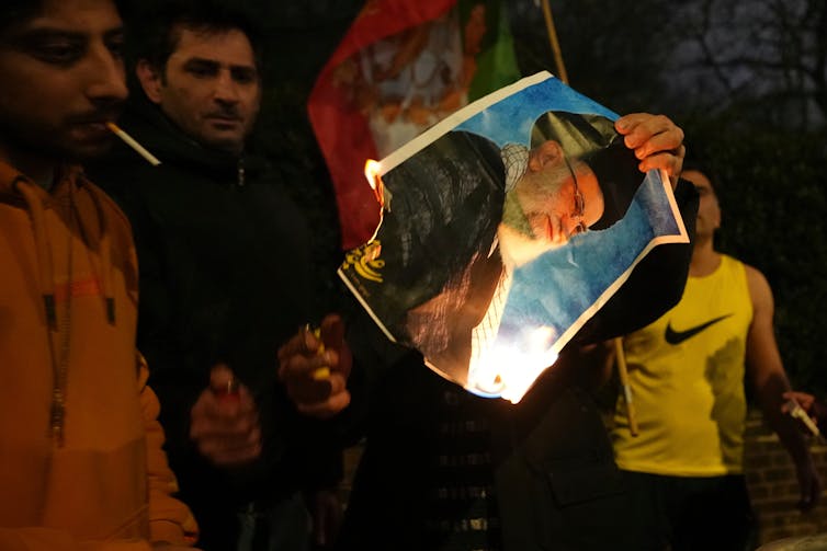 A photo of Ayatollah Ali Khomenei is set on fire by protesters