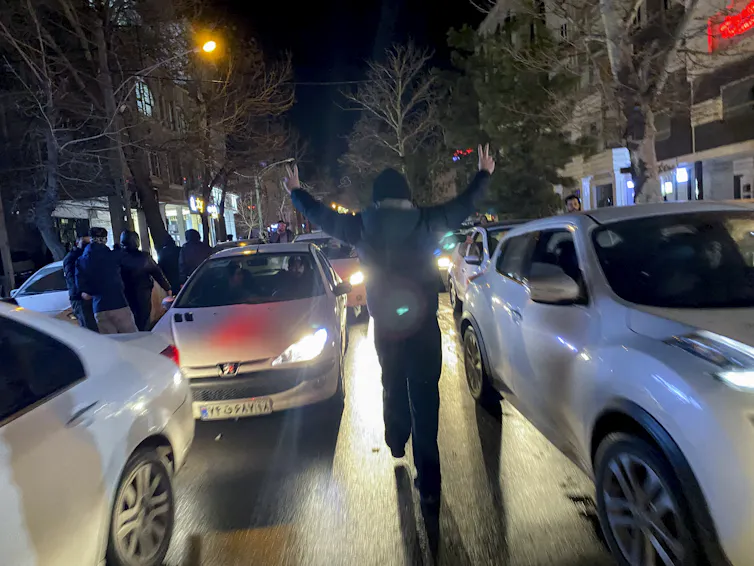 A man walks in between traffic at night.