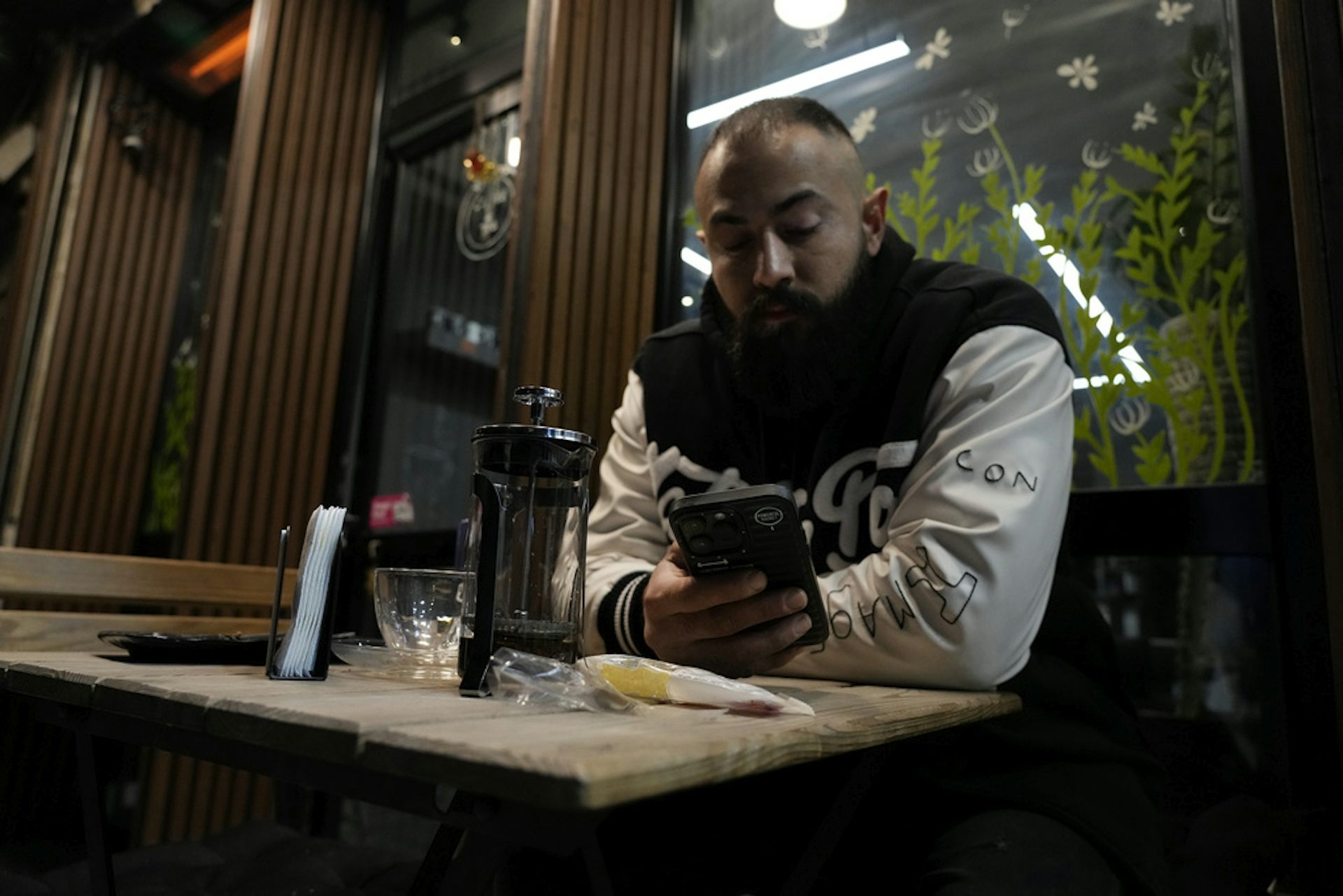 A man looks at his phone at a cafe at night.