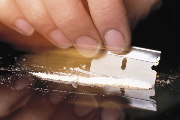 Cutting line of cocaine with tazor blade.