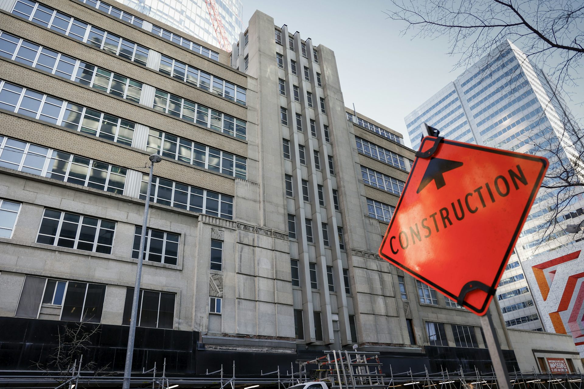 A construction sign seen in front of a large office tower.
