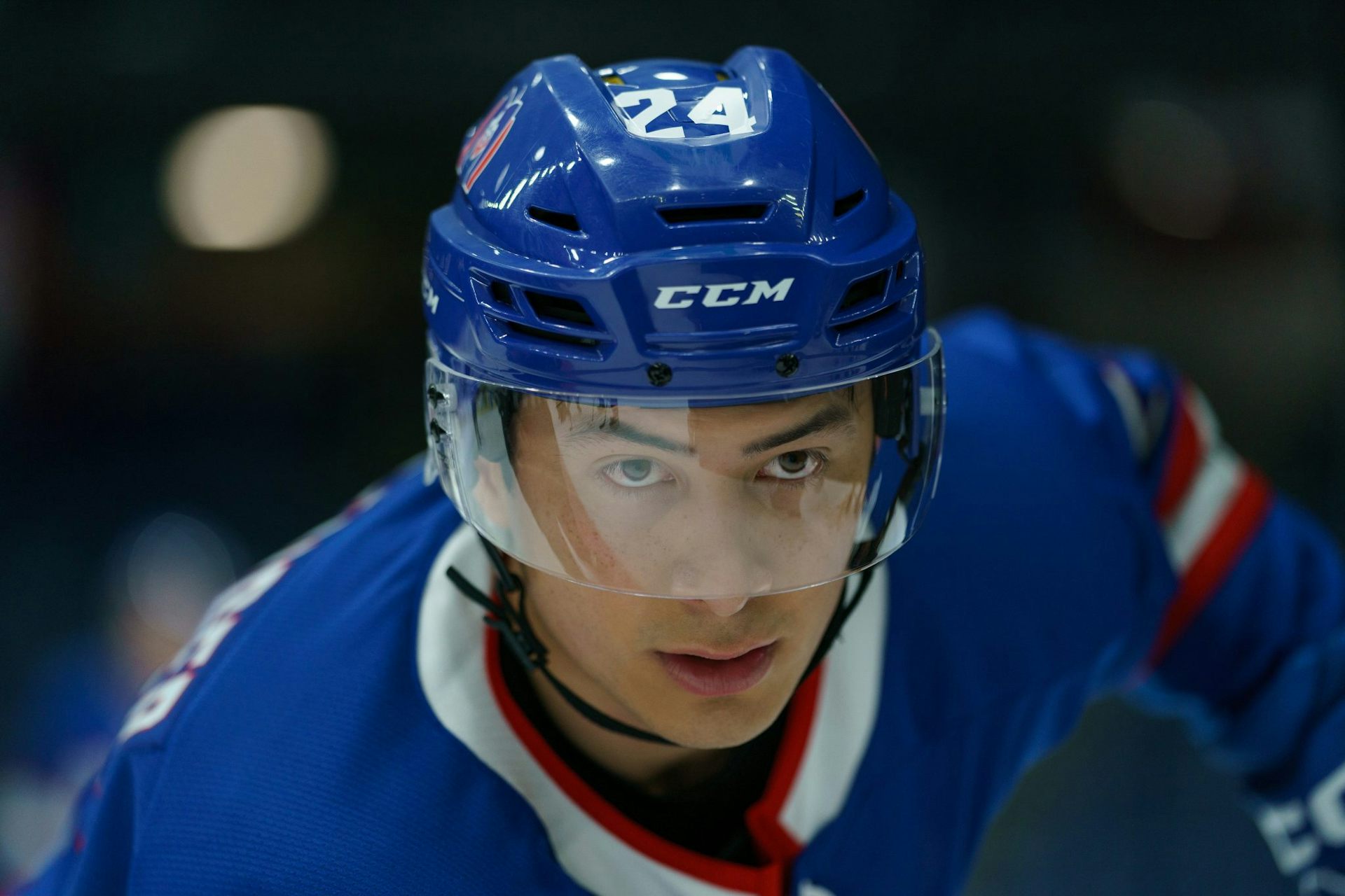 A close-up of the face of an Asian man in a hockey helmet and uniform