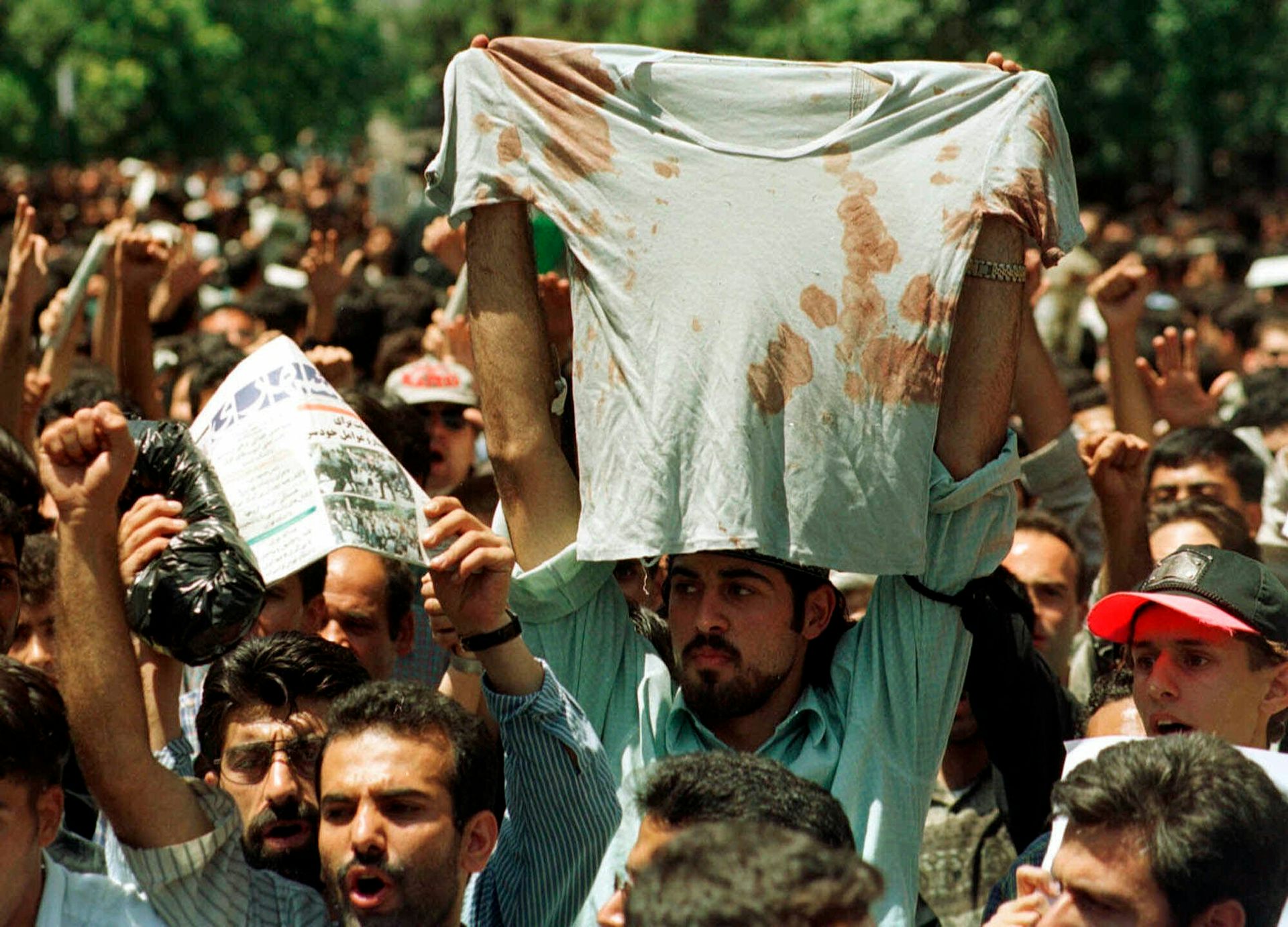A student at a rally in Tehran, Iran, holds up the bloody T-shirt of a friend who was injured (July 12, 1999).