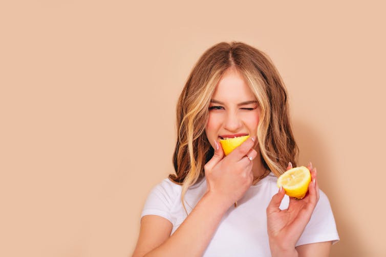 Woman biting into a lemon.