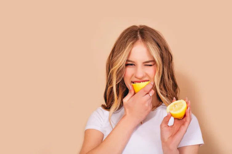 Woman biting into a lemon.