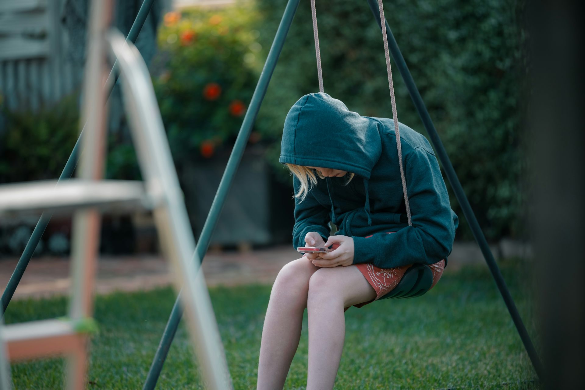 Child alone on swing with phone