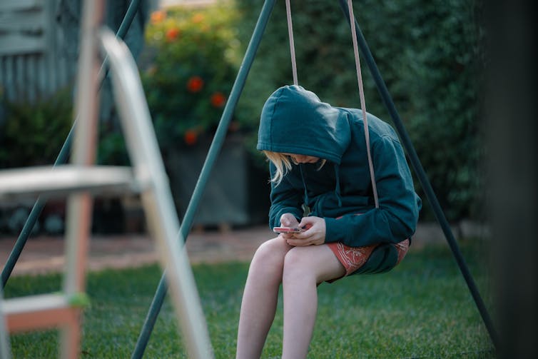 Child alone on swing with phone