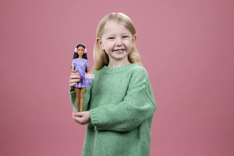 Small blonde girl holding autistic Barbie.