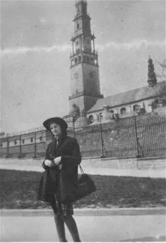 Fotografía en blanco y negro de una mujer joven con abrigo y sombrero oscuro parada frente a una rampa que conduce a un campanario.