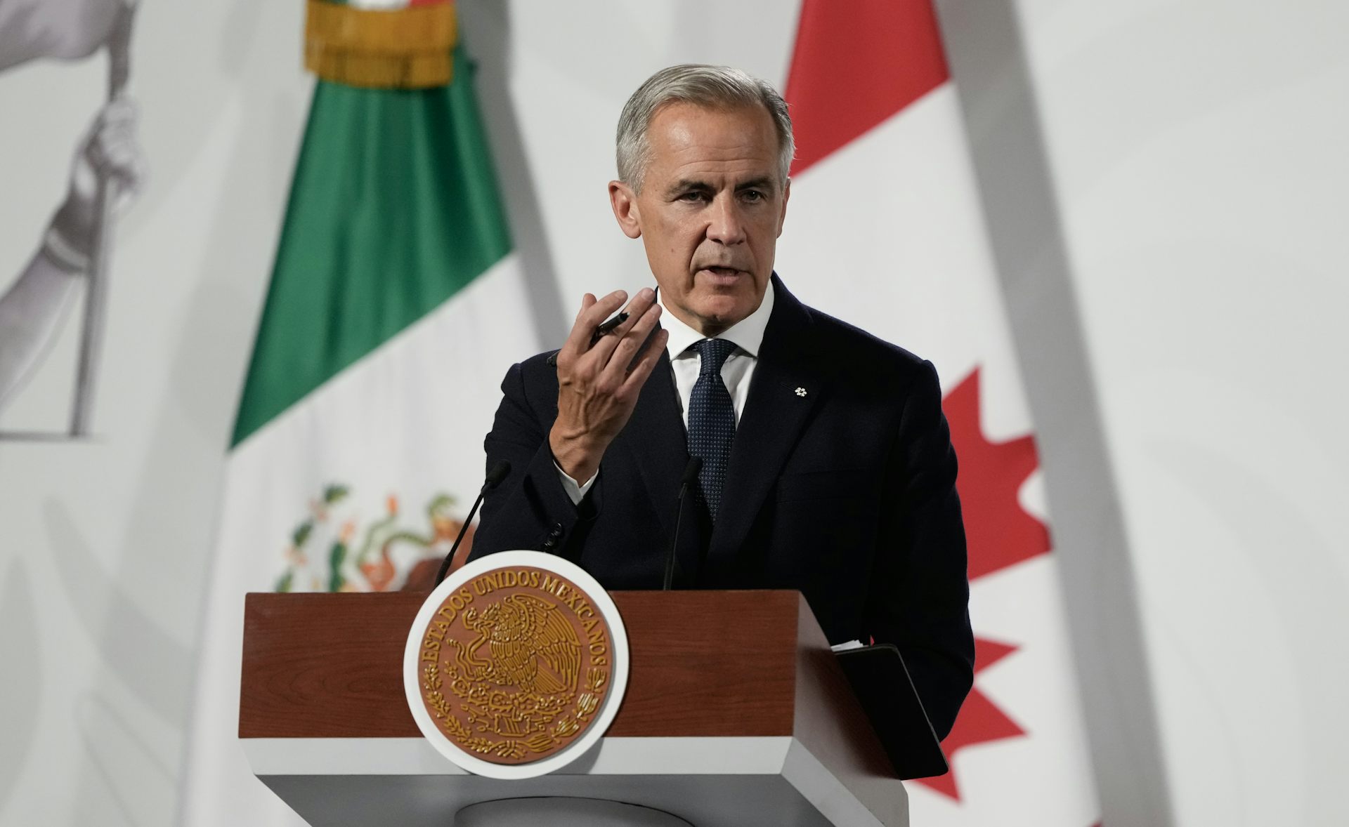 Un hombre de traje habla detrás de un atril.