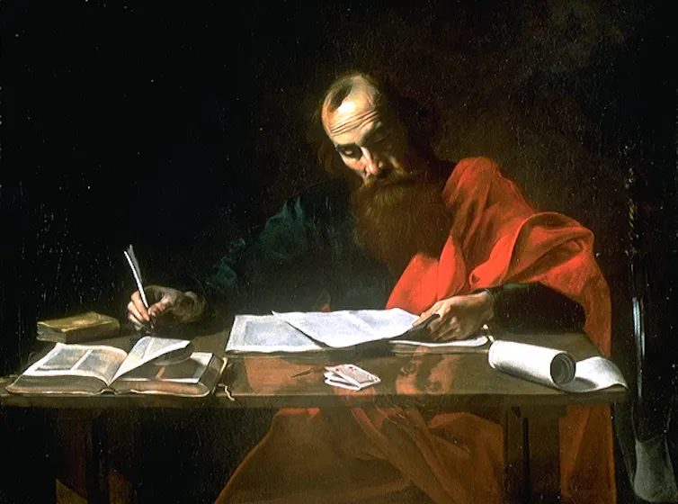 A painting of a bearded man in a red shawl writing at a desk.