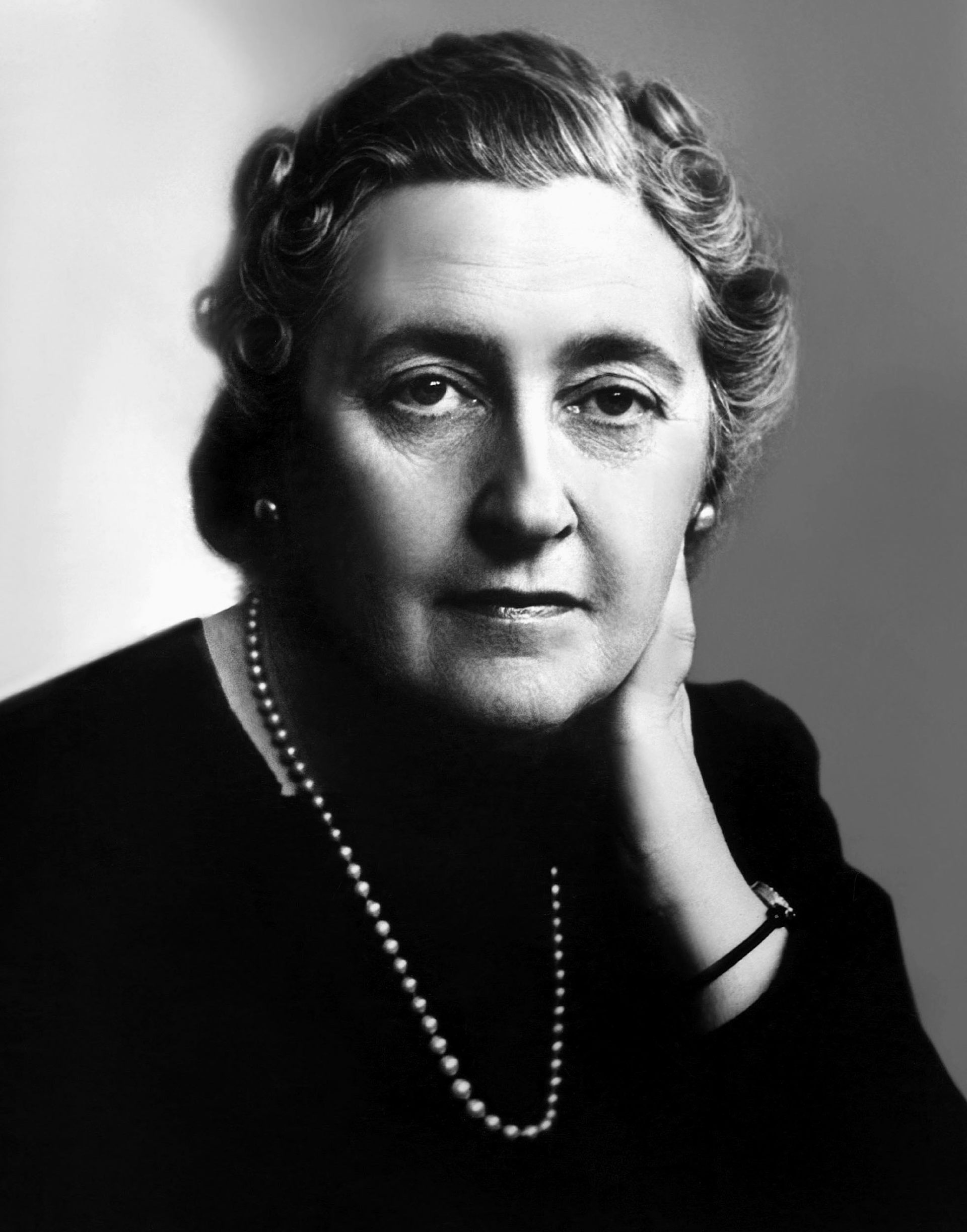 A black and white image of a sombre-looking Agatha Christie dressed in black.