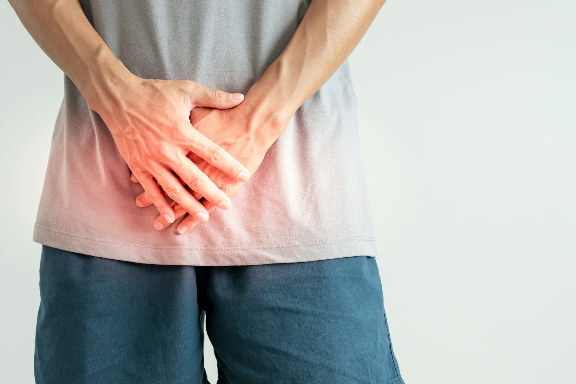 A man holds his hands over his bladder in pain.