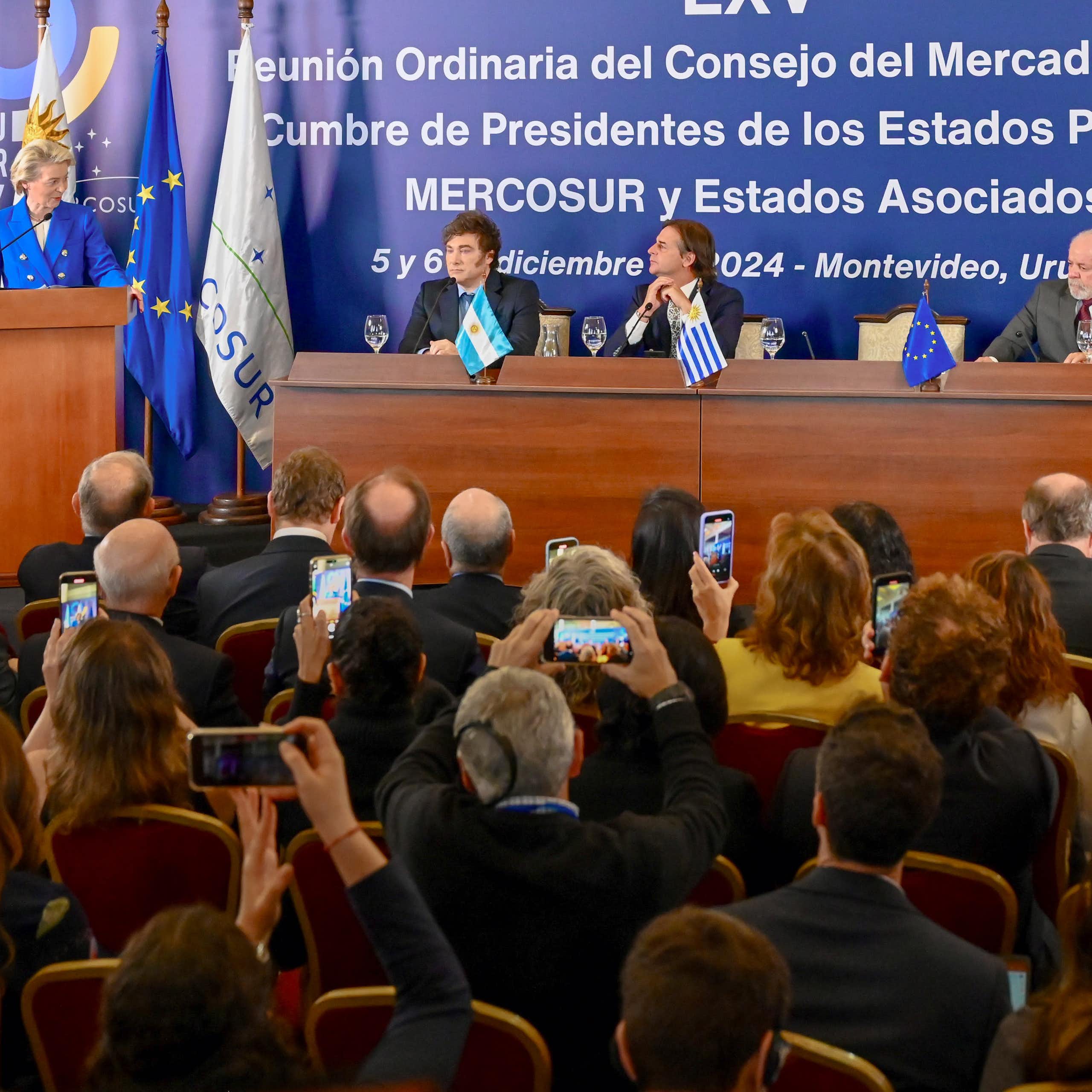 Ursula von der Leyen speaks from a lectern while Javier Milei, Luis Lacalle Pou, Luiz Inácio Lula da Silva and Santiago Peña are seated in a long table next to her
