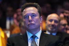 A man with purple light cast over his face in a suit.