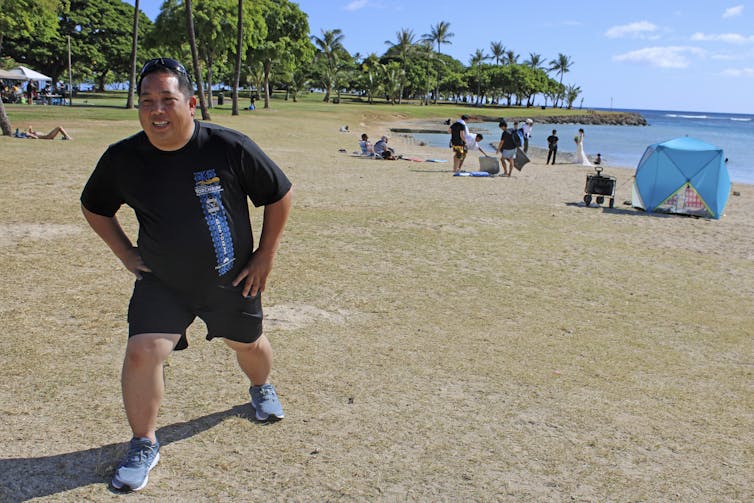 A man stretches on a beach