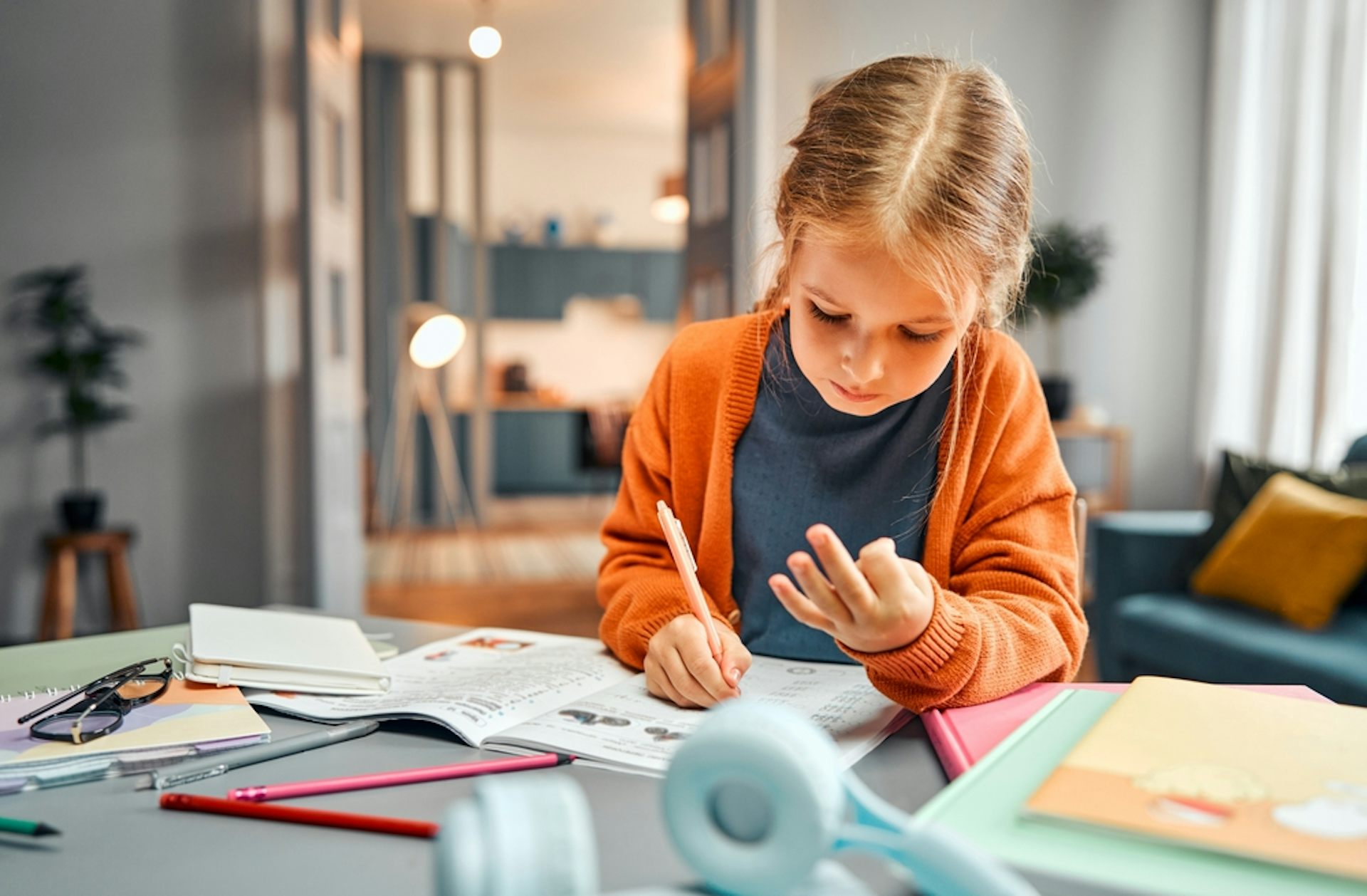 Une petite fille qui compte sur ses doigts en faisant ses devoirs de maths.