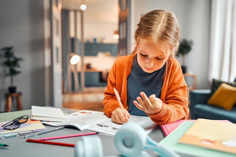 Une petite fille qui compte sur ses doigts en faisant ses devoirs de maths.