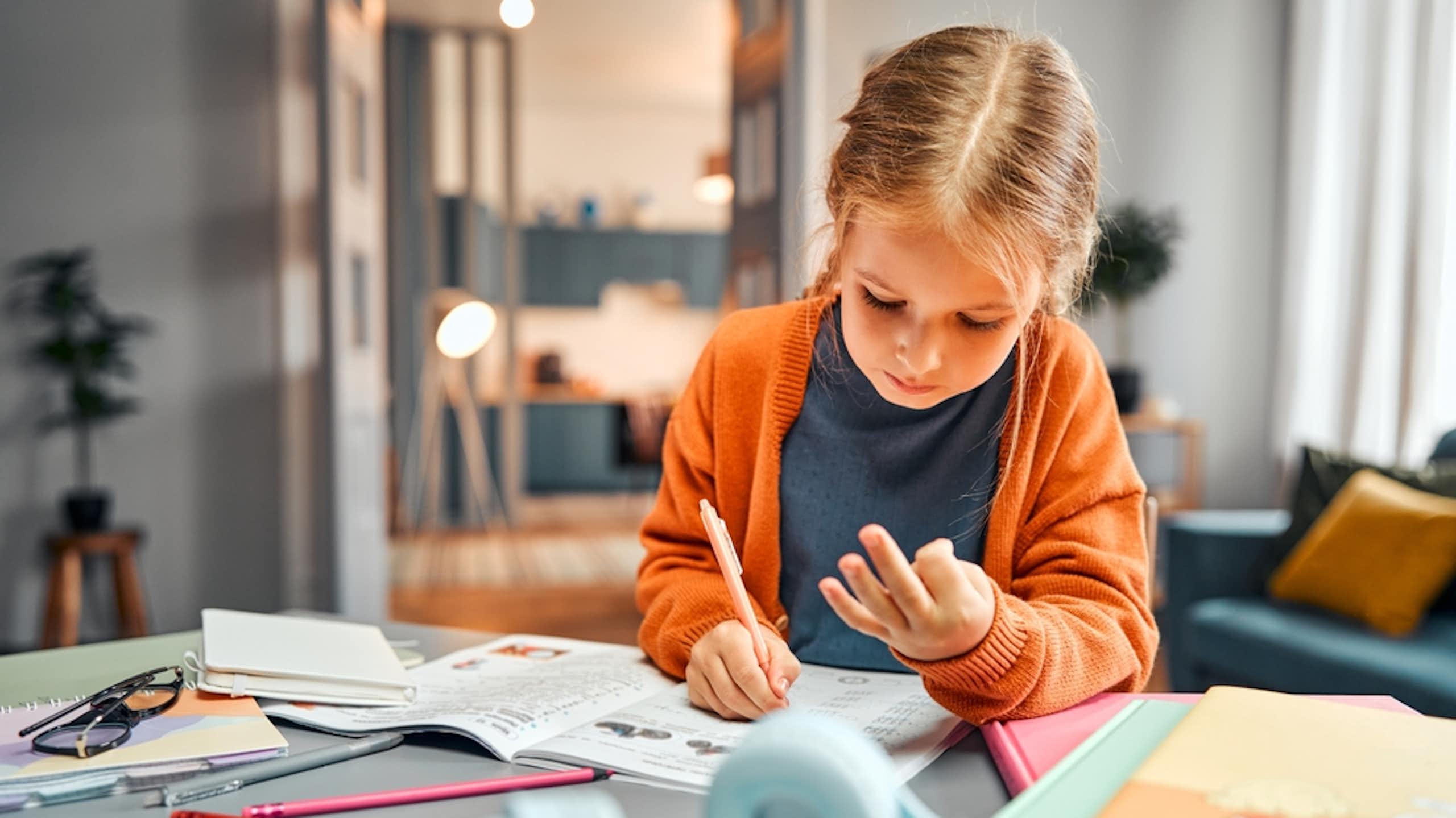 Une petite fille qui compte sur ses doigts en faisant ses devoirs de maths.