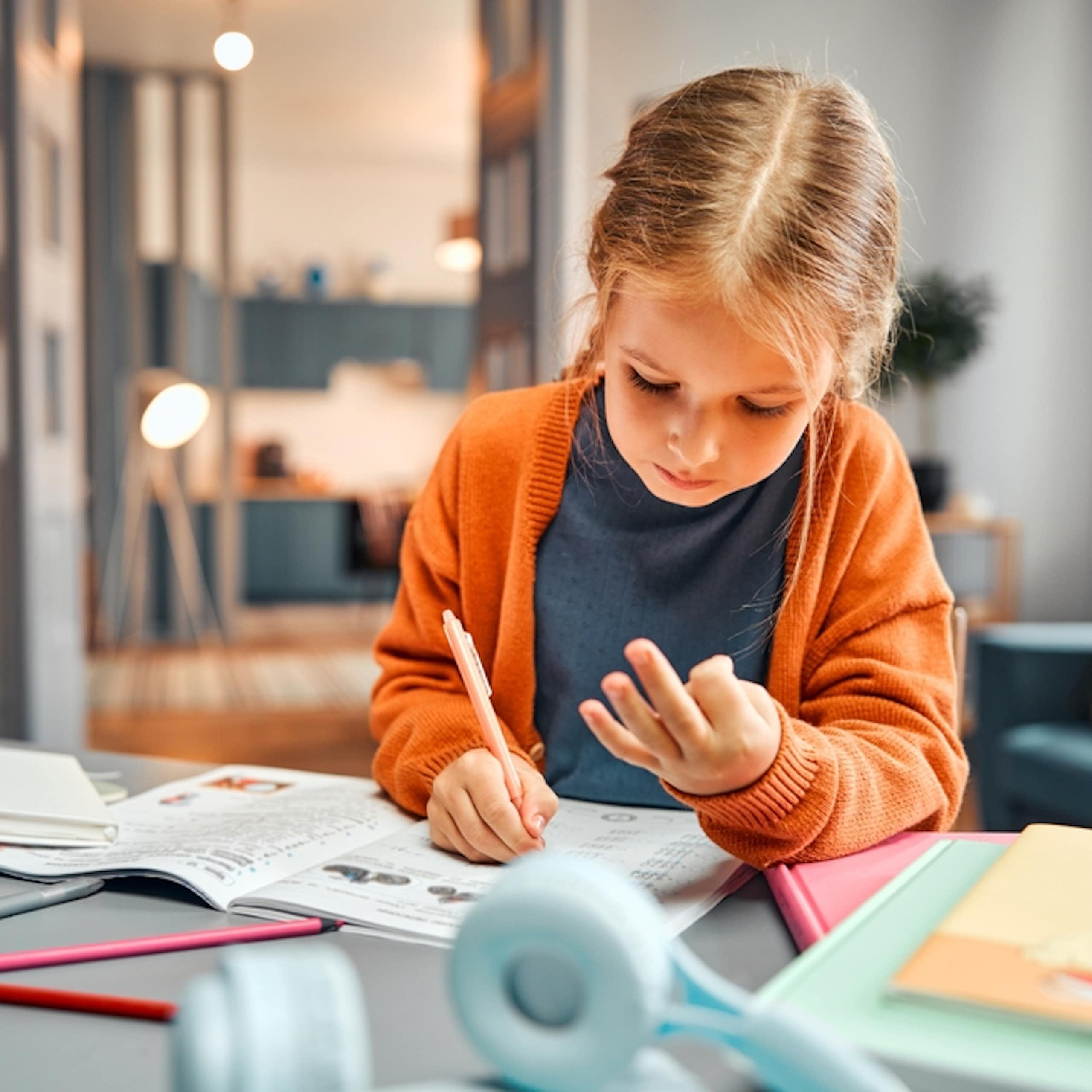 Une petite fille qui compte sur ses doigts en faisant ses devoirs de maths.