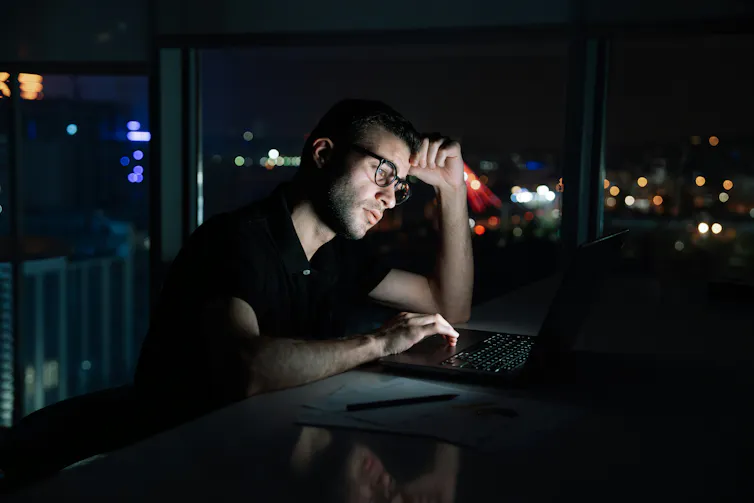 Un homme assis à son bureau, devant son ordinateur