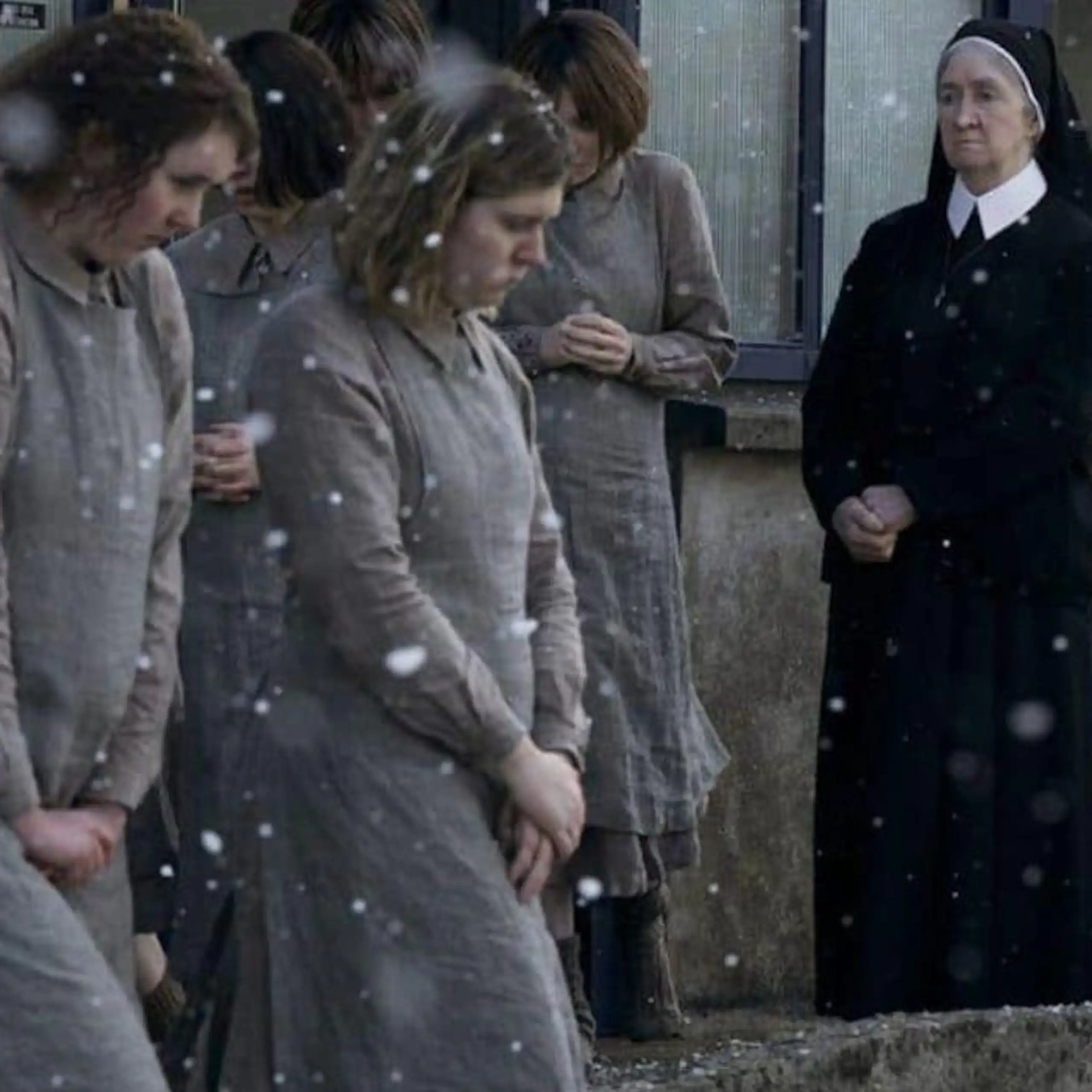 Unas jóvenes caminan bajo la nieve ante la mirada de una monja.