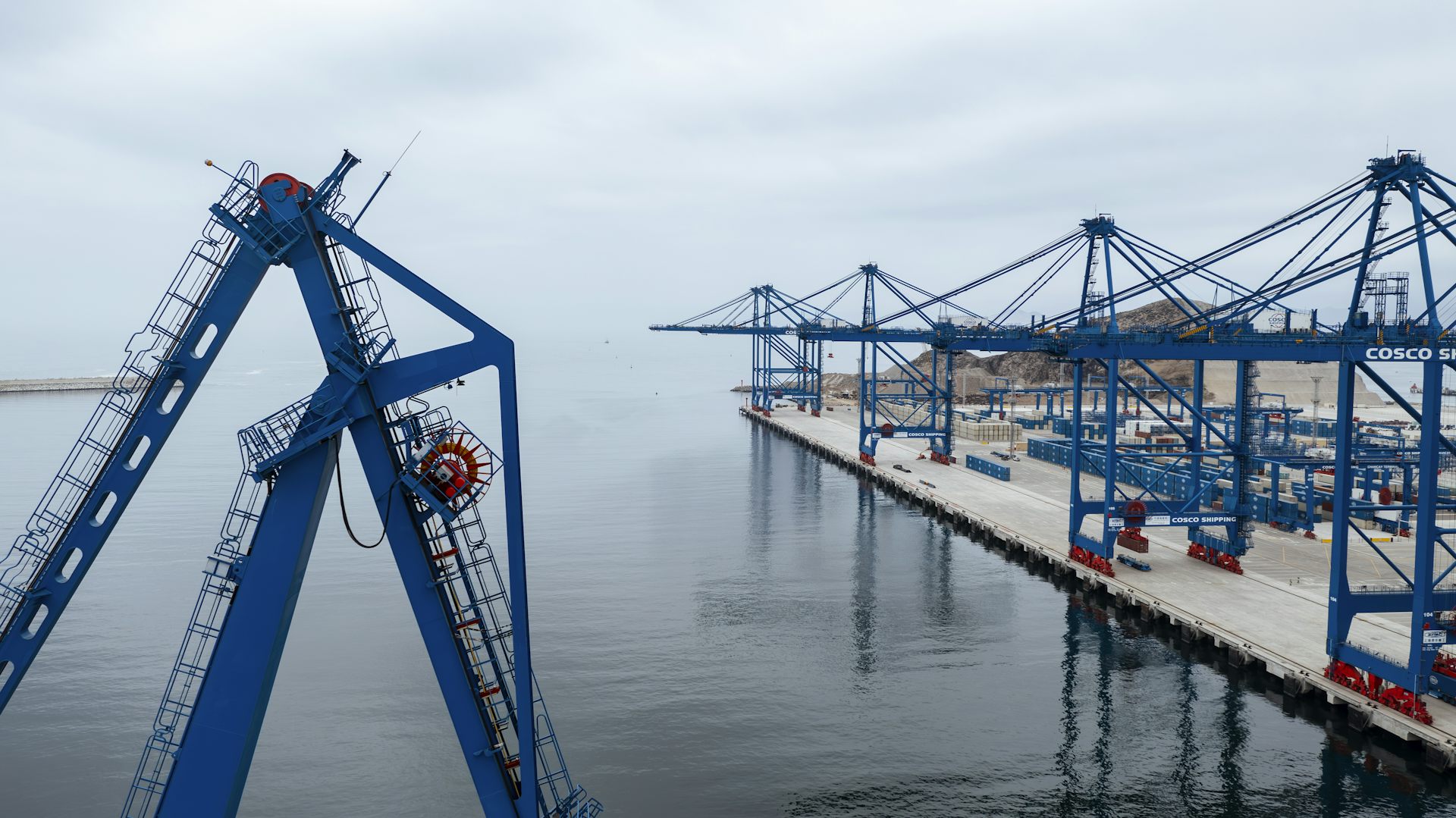 A row of cranes are seen at a dock.