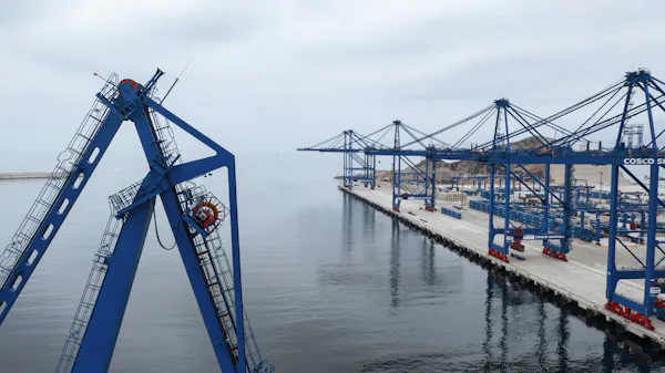 A row of cranes are seen at a dock.