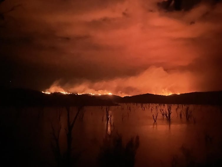 A night image of fires lighting the sky orange above Lake Eildon during the Victorian bushfires.