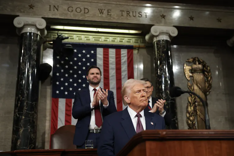 Donald Trump stands in the Capitol and smiles while people applaud