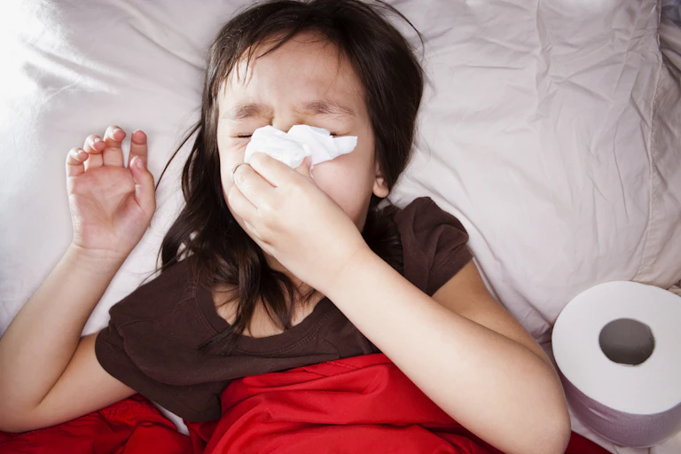 Sick little girl blowing her nose