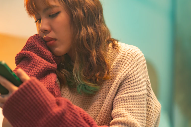 A young woman looking in distress at her phone
