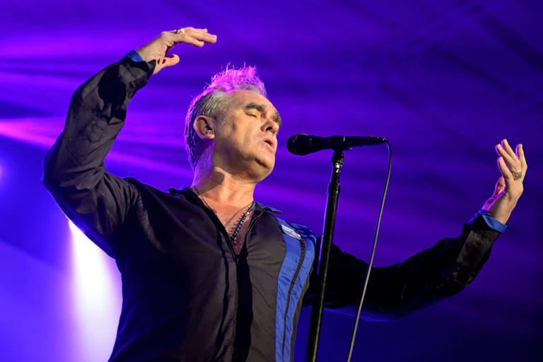 An older man with grey hair on stage singing.