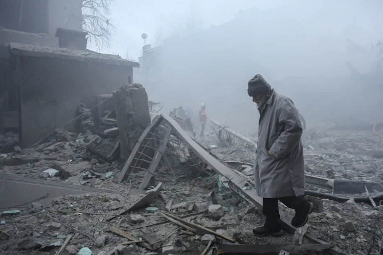 A Ukrainian man walks among the rubble of destroyed buildings.