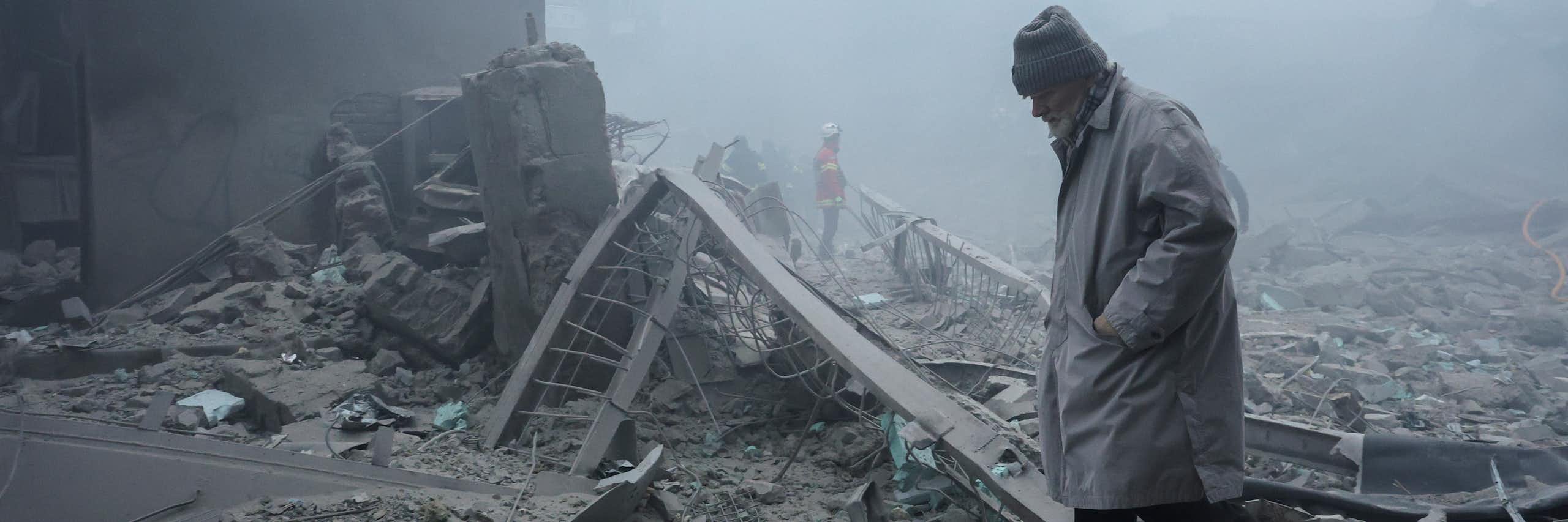 A Ukrainian man walks among the rubble of destroyed buildings.