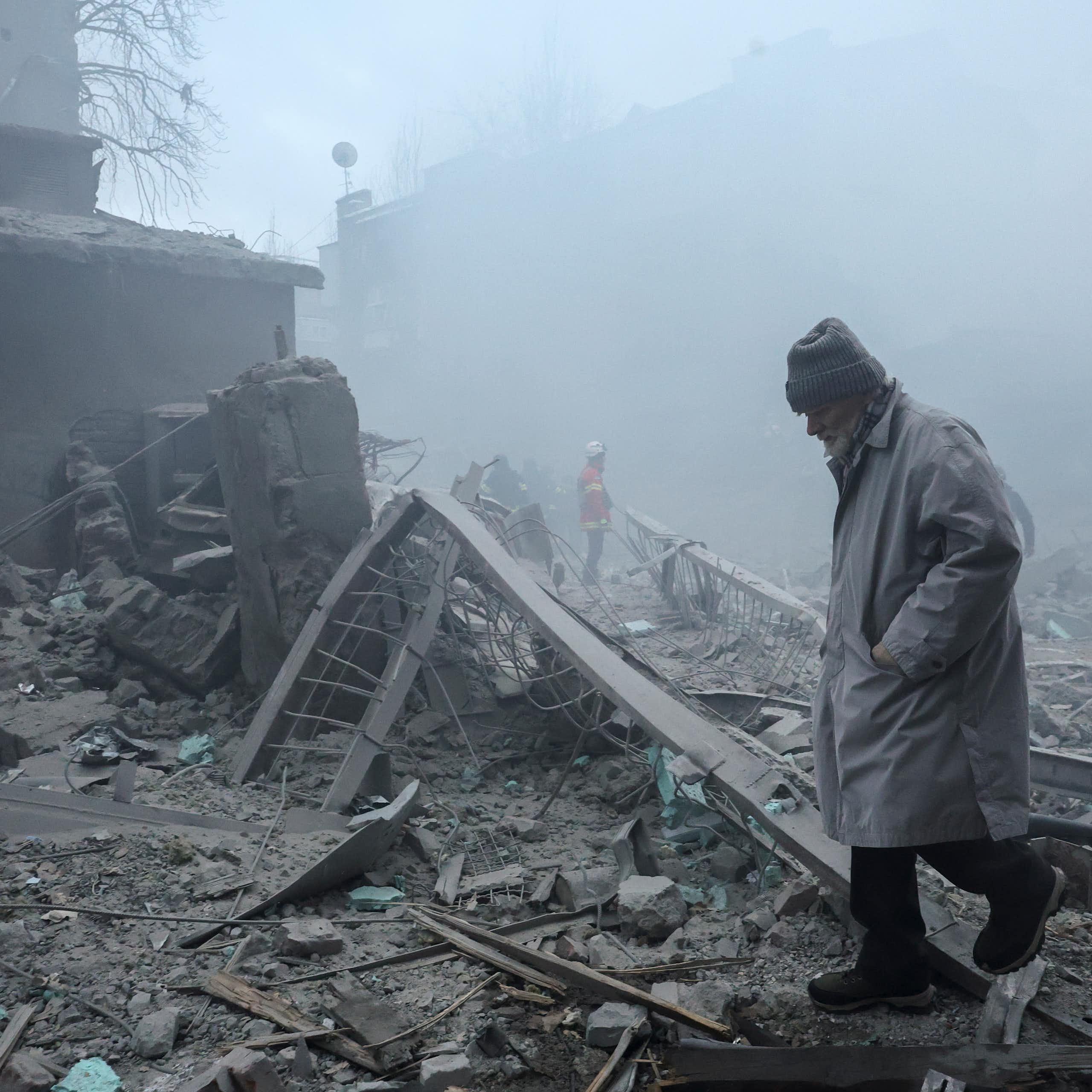 A Ukrainian man walks among the rubble of destroyed buildings.