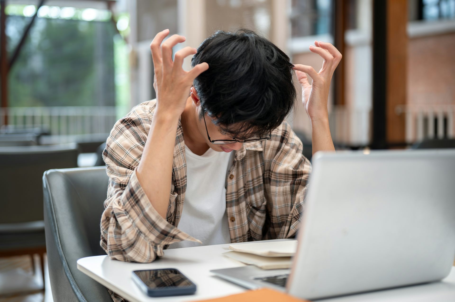 Un chico hace gestos de desesperación ante un ordenador portátil