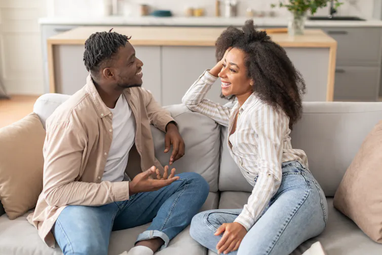 Woman and man sitting on sofa talking together.