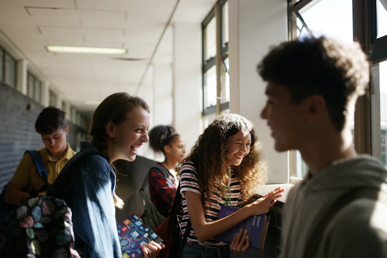 Teenage boys and girls laughing in a school hallway